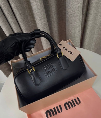 Premium black leather top-handle bag with minimalist embossed logo detail.